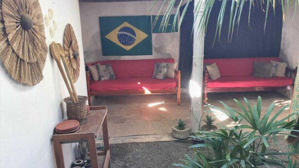 Ein gemütliches Wohnzimmer mit einem roten Sofa, einer brasilianischen Flagge und einem kleinen Tisch mit einem Korb.