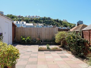 Un patio con cerco de madera, plantas en macetas y vista de casas en una colina.