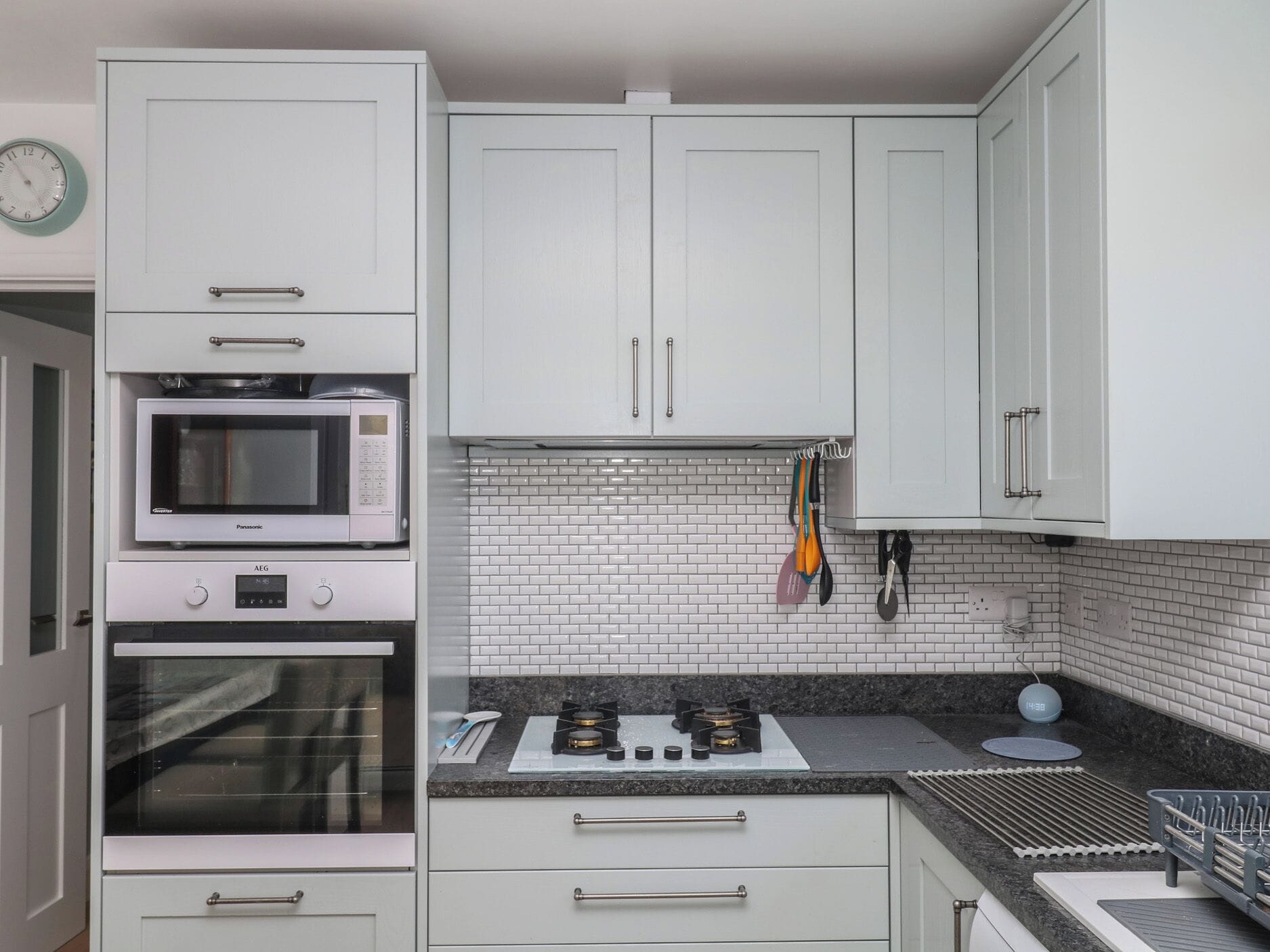A kitchen with white cabinets, a microwave, oven, gas stove, and a tiled backsplash.