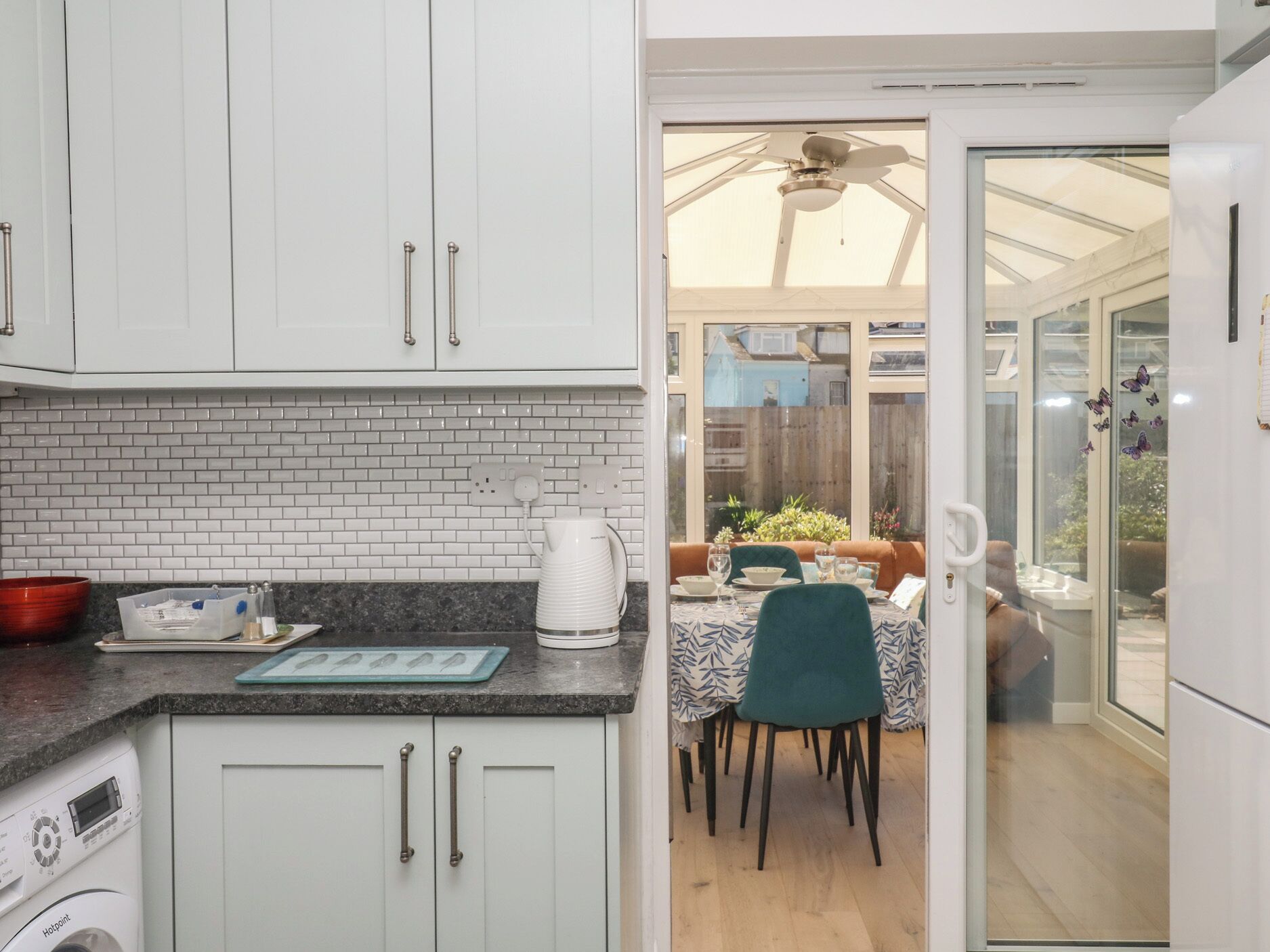 A kitchen with white cabinets, a granite countertop, and a dining area with a table and chairs.