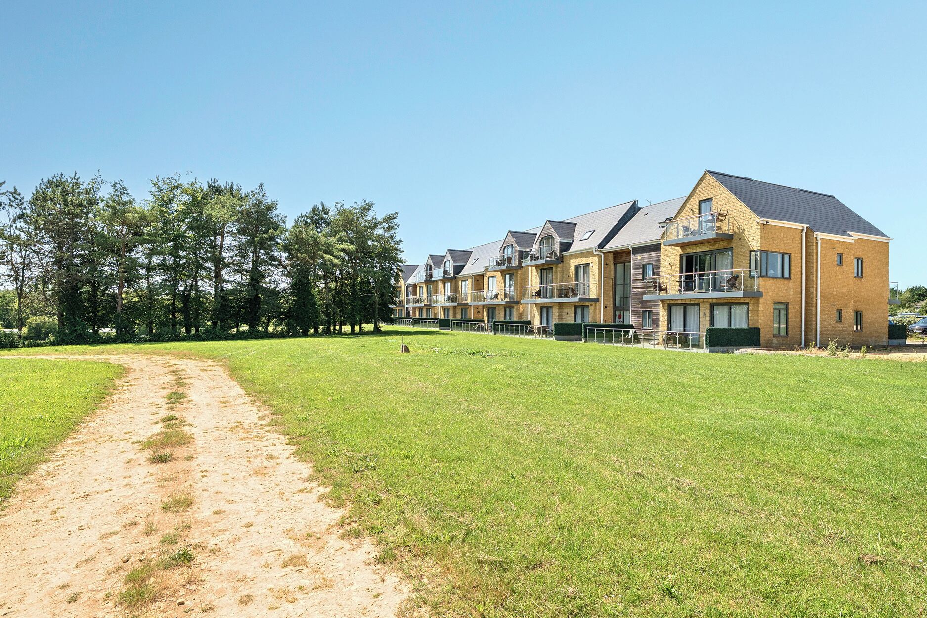 A row of multi-story residential buildings with a dirt path leading to the entrance.