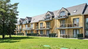 A row of multi-story residential buildings with balconies, a grassy lawn, and a tree. - Cotswolds Apartment 4, Sleeps 9 (Chipping Norton)