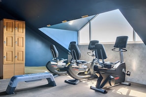Ein Fitnessraum mit Trainingsgeräten, einer Step-Plattform und einem Holzschrank.