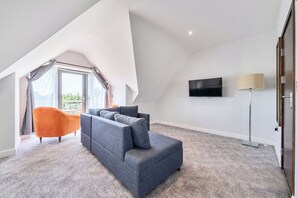 A modern living room with a grey sectional sofa, a flat-screen TV, and a floor lamp. - Cotswolds Apartment 4, Sleeps 9 (Chipping Norton)