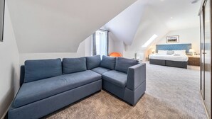 A modern bedroom with a sectional sofa, a bed, and a skylight. - Cotswolds Apartment 4, Sleeps 9 (Chipping Norton)