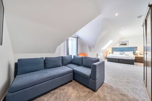 Ein modernes Schlafzimmer mit einer Eckcouch, einem Bett und einem Oberlicht.