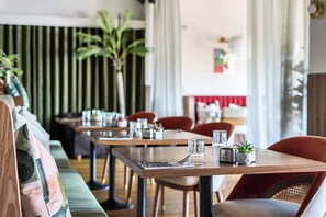 Ein Restaurantinnenraum mit Holztischen, Stühlen und einer Zimmerpflanze auf den Tischen.