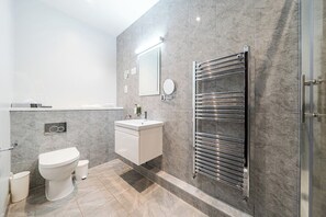Et moderne badeværelse med toilet, håndvask og håndklædestige.