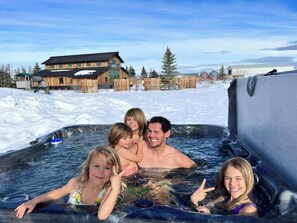 Eine Familie in einer Whirlpoolanlage, im Hintergrund eine Holzhütte.