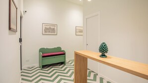 A hallway with a green sofa, a wooden bench, and a pinecone decoration. - Luxury Boutique Apartment 1 in Palermo City Center, near the Central Station (Palermo)