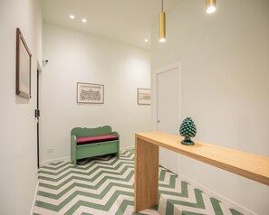Ein Flur mit einem grünen Sofa, einer Holzbank und einer Kiefernzapfen-Dekoration.