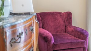 A room with a wooden dresser, a laptop, a pink chair, and a vase with flowers. - Luxury Boutique Apartment 1 in Palermo City Center, near the Central Station (Palermo)