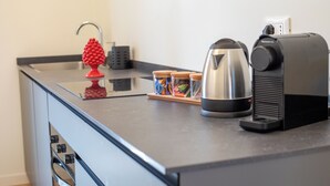A kitchen counter with a kettle, a coffee machine, and a red fruit-shaped object. - Luxury Boutique Apartment 1 in Palermo City Center, near the Central Station (Palermo)