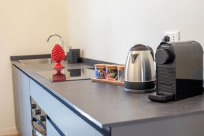 Eine Küchenarbeitsplatte mit einem Wasserkocher, einer Kaffeemaschine und einem roten, obstförmigen Gegenstand.