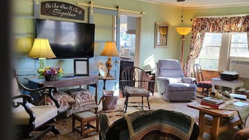 A cozy living room with a ceiling fan, a television, and a fireplace.