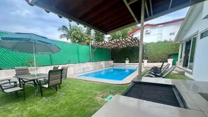 A backyard with a swimming pool, a covered patio area, and a lawn. - Villa Nido Lomas de Cocoyoc: Private Pool and Garden (Fraccionamiento Lomas de Cocoyoc)