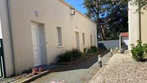 A building with a white door, small windows, and a gravel pathway. - Joalland's Cozy Retreat, 50 meters from the beach (La Plaine-sur-Mer)