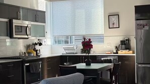 A modern kitchen with a dining area, a built-in oven, a microwave, and a refrigerator. - The May Townhome - Upper (Seattle)