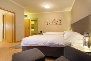 Habitación de hotel con una cama, una mesita de noche con lámpara, una silla y un armario verde.