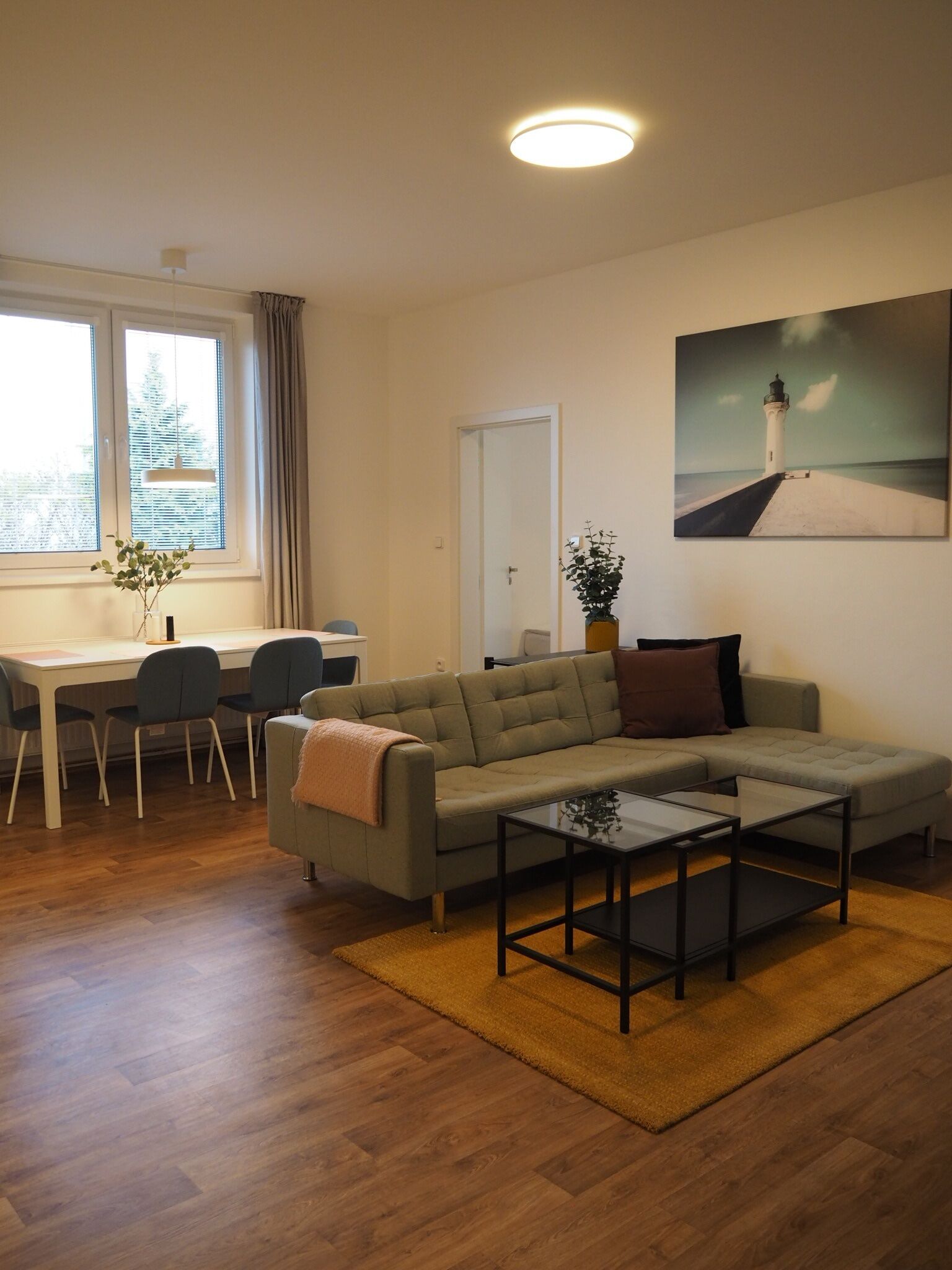 A modern living room with a sofa, a coffee table, and a dining area with chairs and a table.