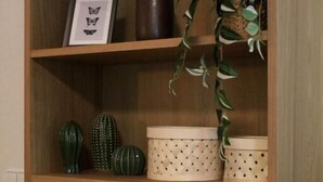 A wooden shelf with various decorative items including a framed picture, a vase, and a potted plant.