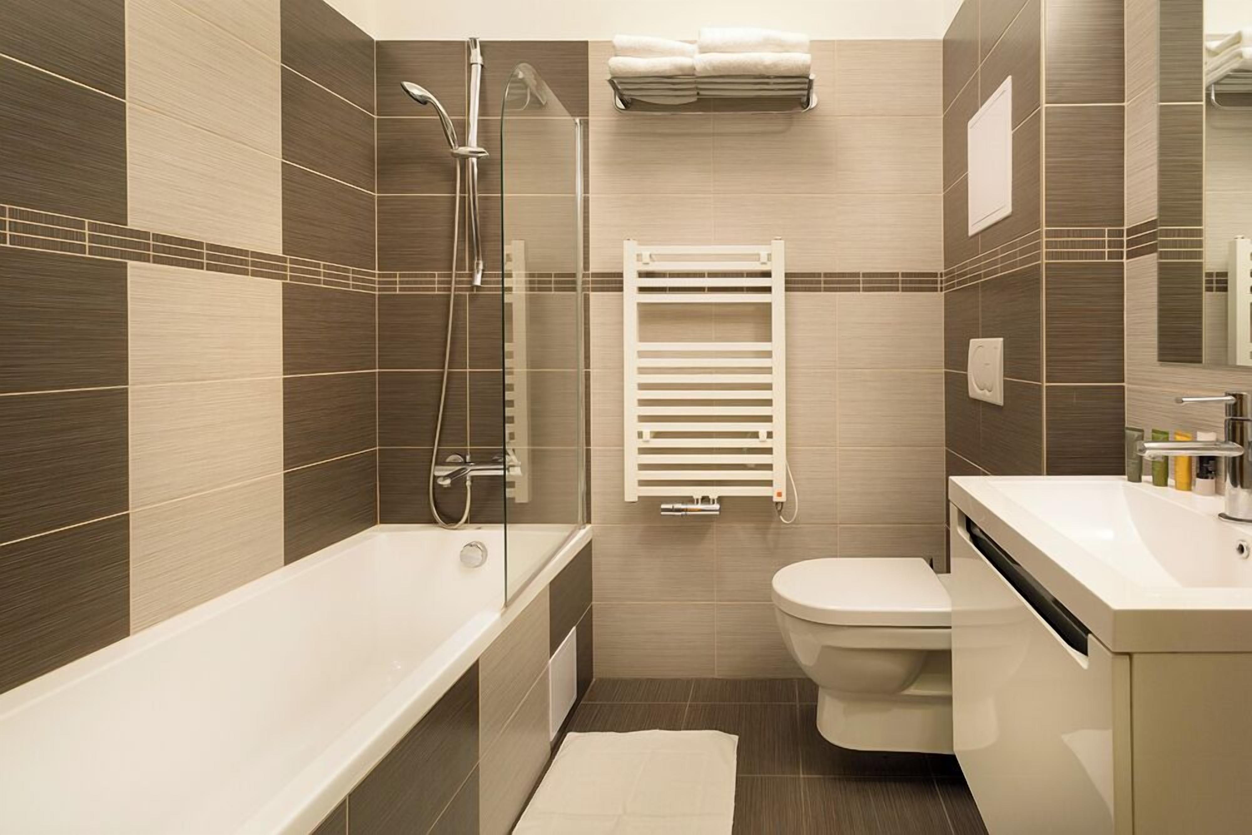 A modern bathroom with a bathtub, shower, toilet, and a towel rack.