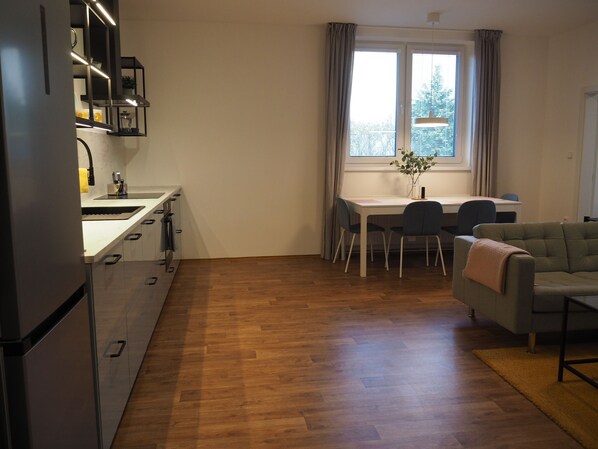 Un espacio habitable compacto con kitchenette, comedor y zona de estar.