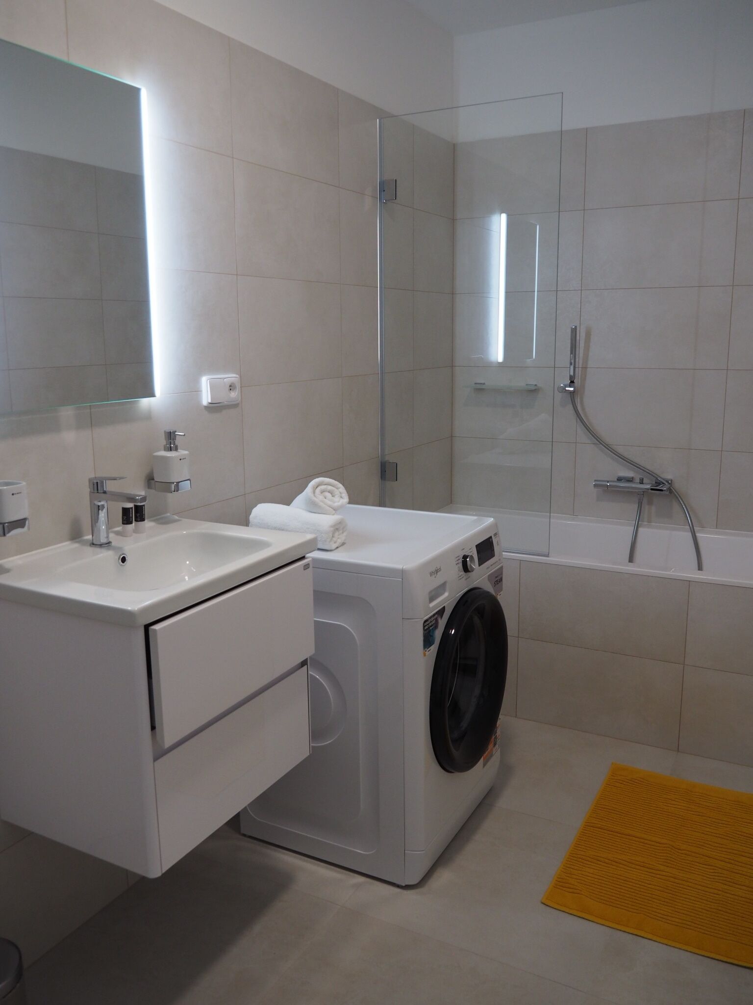 Un baño moderno con lavadora, lavamanos y bañera.
