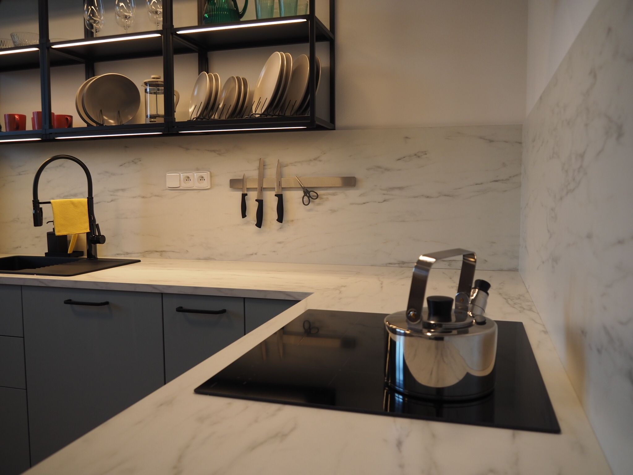 A modern kitchen with a black countertop, a built-in stove, and a sink.