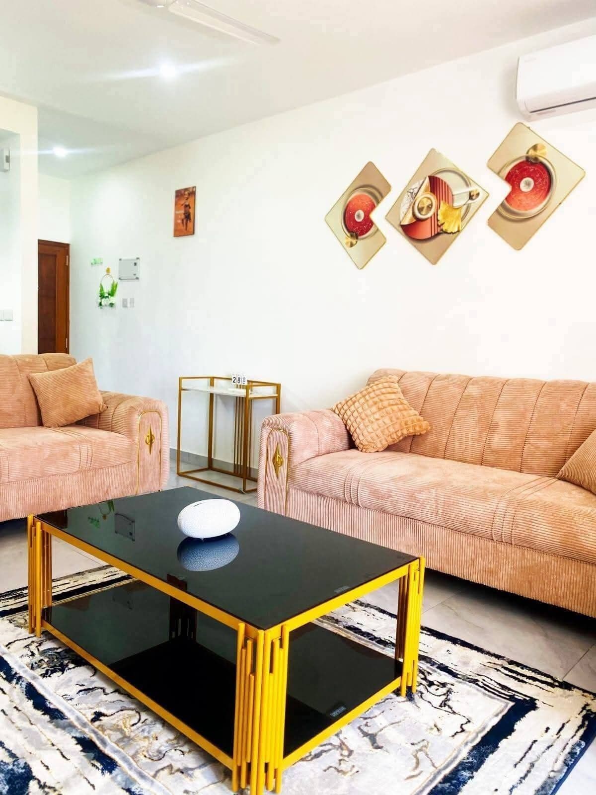 Sala de estar com dois sofás, uma mesa de centro e quadros nas paredes.
