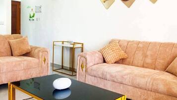 Sala de estar com dois sofás, uma mesa de centro e quadros nas paredes.