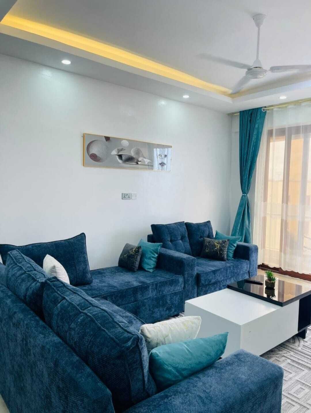 A modern living room with two sofas, a coffee table, and a ceiling fan.