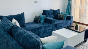 Uma sala de estar moderna com dois sofás, uma mesa de centro e um ventilador de teto.