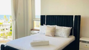 Quarto de hotel com cama, mesa de cabeceira, janela com cortinas e vista para o exterior.