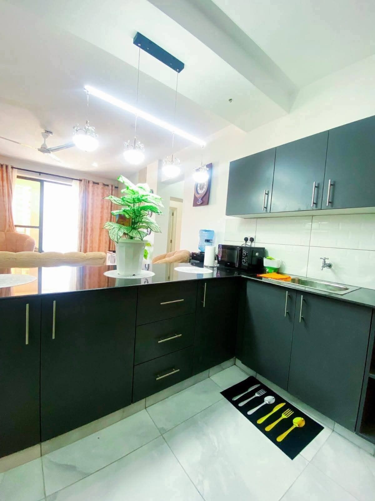 A modern kitchen with dark cabinets, a central island, and a dining area with a view.