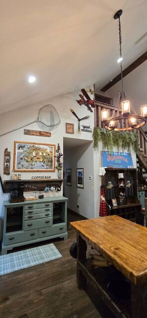 Une pièce chaleureuse avec une table en bois, un coin café et un luminaire suspendu.