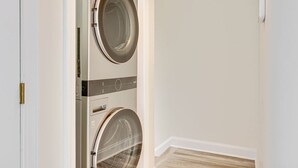 A laundry room with two stacked washing machines and a door.