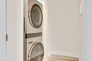 A laundry room with two stacked washing machines and a door. - Atlantic Beach Escape | Walk to Sand & Boardwalk (Atlantic Beach)