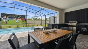 Une terrasse avec une piscine, une table en bois et un espace barbecue.