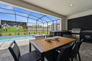 A patio with a pool, a wooden table, and a grill area. - Orlando Most Incredible Themed 10br Villa (Clermont)