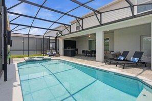 Piscina com estrutura de vidro, área de estar ao ar livre e churrasqueira.