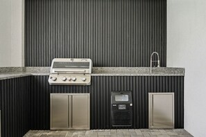 An outdoor kitchen with a built-in grill, a water dispenser, and a sink. - Orlando Most Incredible Themed 10br Villa (Clermont)