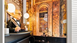 Un espace bar avec un mur en marbre, une grande fenêtre en arc de cercle et un barman.