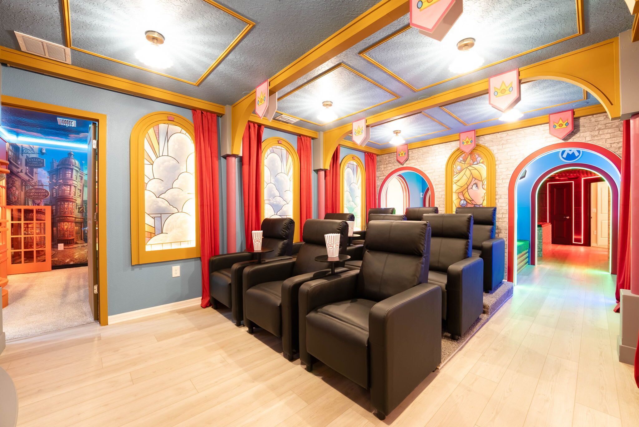 A theater room with rows of black leather chairs, a popcorn machine, and a large poster of a wizarding world on the wall.