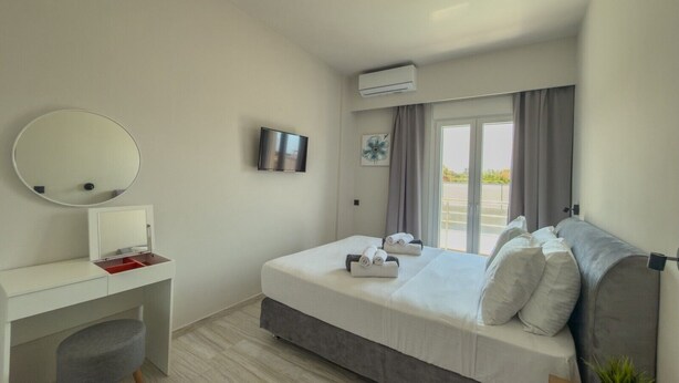 A modern hotel room with a bed, a desk, a TV, and a window with curtains. - Eligio Luxury Residence with Private Jacuzzi & Sea View (Gournes Gouvon)