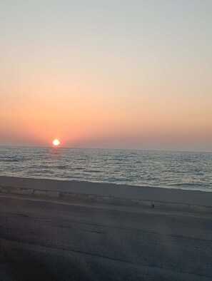 Ein Sonnenuntergang über einem Gewässer, im Vordergrund eine Straße.