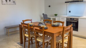 A dining area with a wooden table and chairs, a bench, a world map on the wall, and a kitchen with a stove and oven. - Eligio Luxury Residence with Private Jacuzzi & Sea View (Gournes Gouvon)