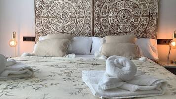 A hotel room with a large bed, floral bedspread, two nightstands with lamps, and a decorative headboard.