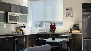 A modern kitchen with a dining area, a built-in oven, a microwave, and a refrigerator. - The May Townhome - Full Home (Seattle)