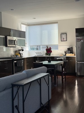 Una cocina moderna con comedor, horno empotrado, microondas y refrigerador.